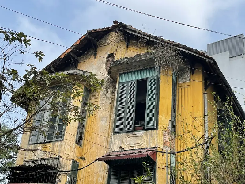 An old yellow house with green shutters in Hanoi